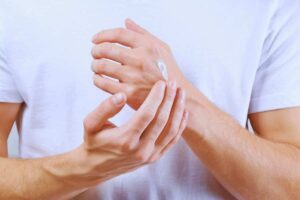 Due mani con la crema sulla pelle